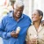 older couple walks down city sidewalk while holding ice cream cones